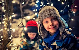 Junge mit Mütze im Schnee mit Lichterkette 