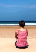 Frau am Strand aufs Meer schauend