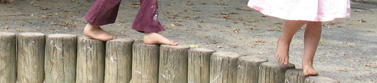 Kinder balancieren barfuß auf Holzpfosten