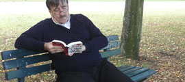 Senior liest Buch auf einer Parkbank