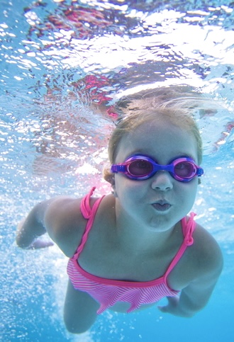 Mädchen taucht unter Wasser mit rosa Schwimmbrille