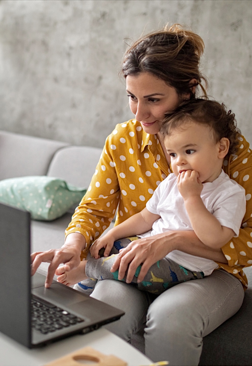 Frau mit Baby sitzt an einem laptop 