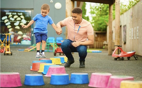 Junger Erzieher spielt im Kindergarten mit einem kleinen Jungen 