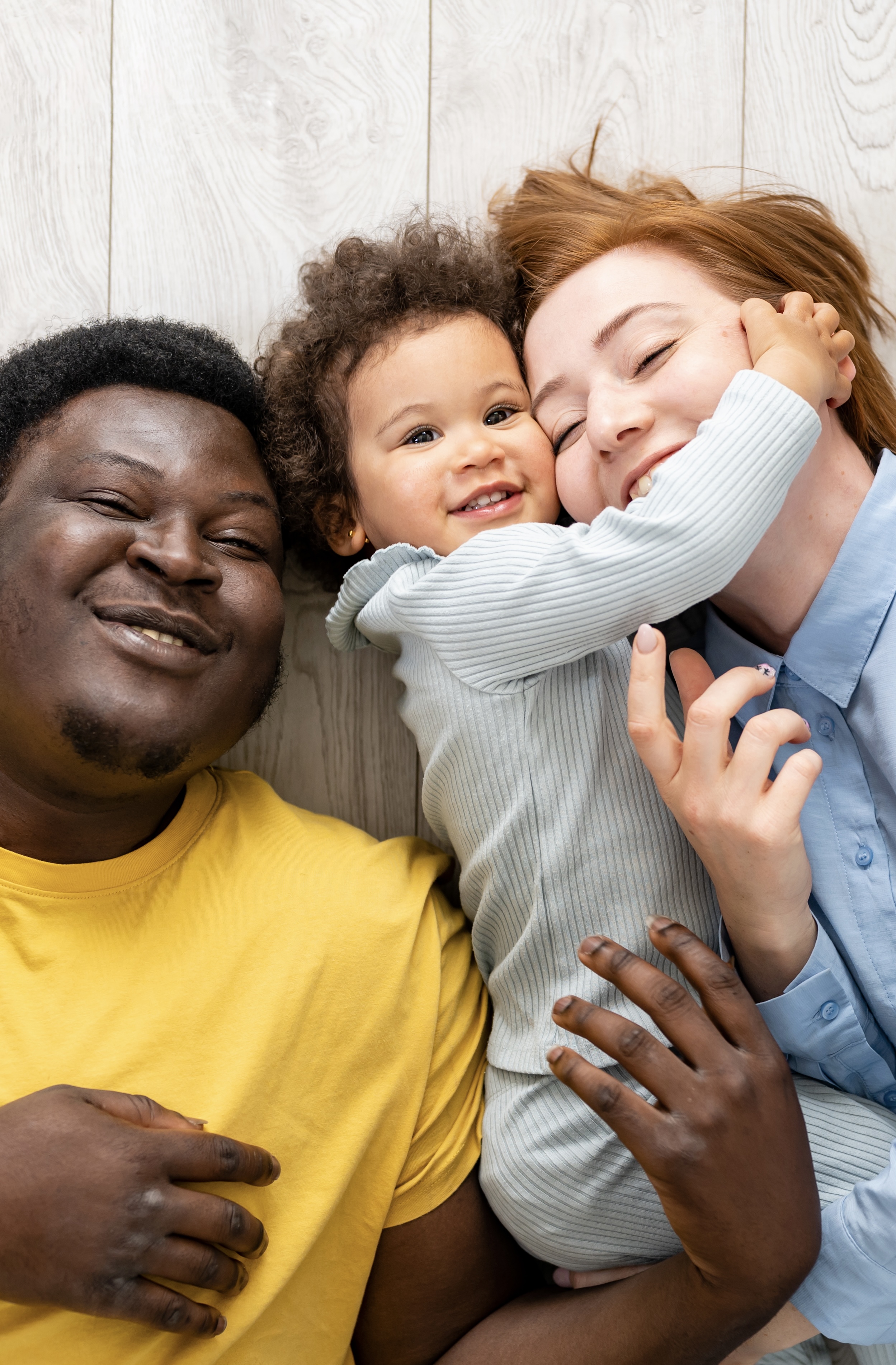 Schwarzer Vater, weiße Mutter und Baby lachen ins Bild 