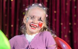 Bunt geschminktes Mädchen mit clownsnase lachend