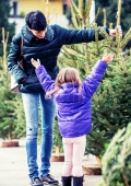 Frau mit Kind begutachten Weihnachtsbäume