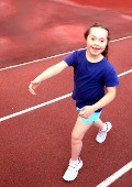 Mädchen joggt lachend auf Aschenbahn