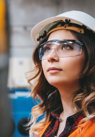 Junge Frau mit schutzbrille und Helm an einem Ger&auml;t