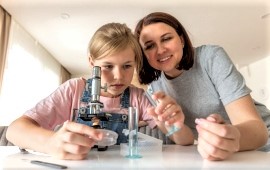 Mädchen untersucht etwas am Mikroskop - Mutter hilft