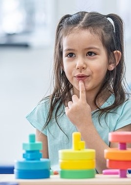 M&auml;dchen bei einer Logop&auml;din zeigt auf seinen Mund