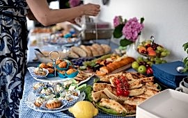 Frau steht an einem bunten Buffet mit Speisen