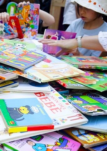 Kind und Erwachsene st&ouml;bern in bunten Kinderb&uuml;chern.