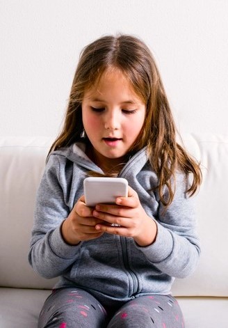 Ein Kind hält ein Smartphone und schaut darauf